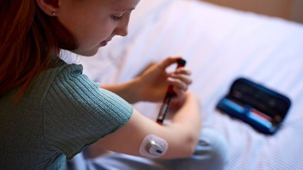 Young girl with type 1 diabetes is monitoring her insulin and blood sugar level