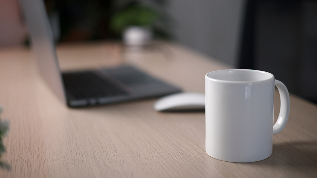 Cup of coffee laying on a desk beside a laptop