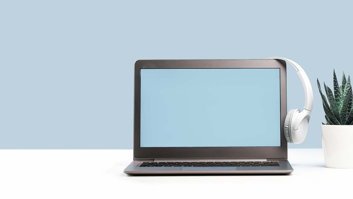 Laptop. Mockup screen and headphones on white desk and plain background banner. Distant learning. working from home, online courses or support minimal concept. Helpdesk or call center headset