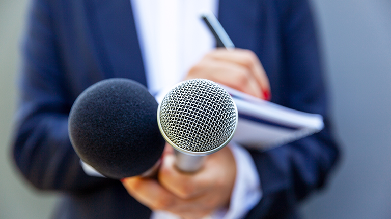 reporter holding a microphone out for an interview