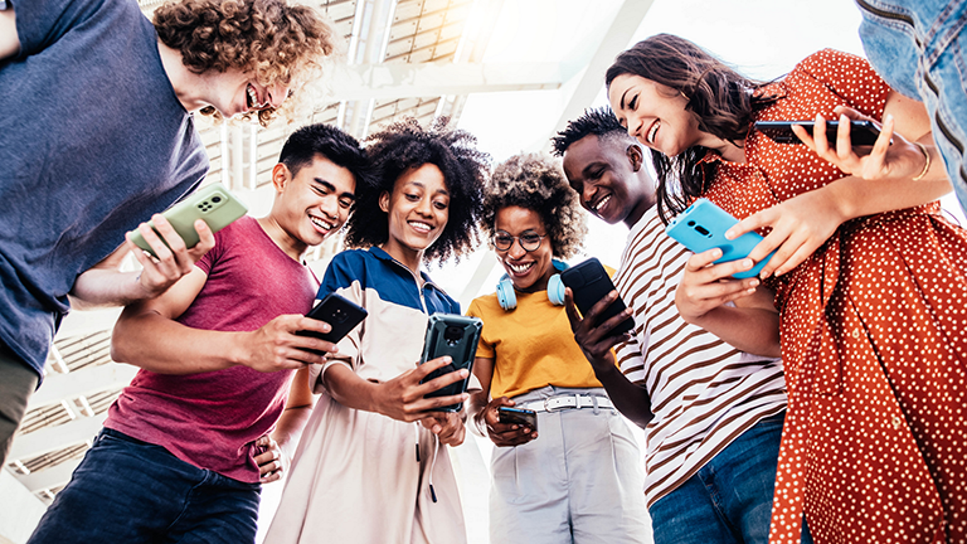 young adults standing around holding phones and engaging on social media