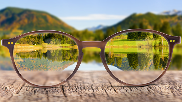 Eyeglasses on a tabletop with clear image loking through lenses and out-of-focus background 