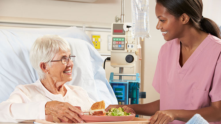 dietitian visitng with hospital patient eating a healthy meal