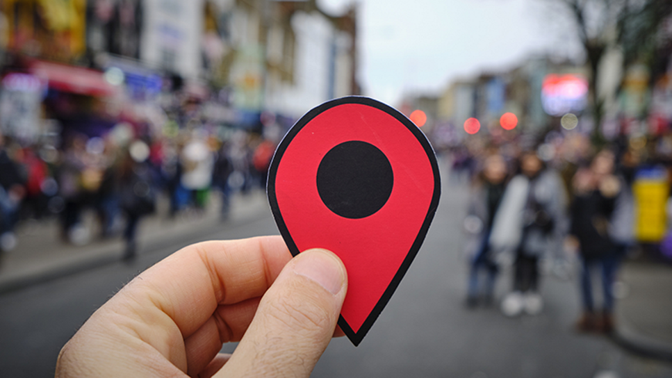 holding a location symbol while standing in a town square