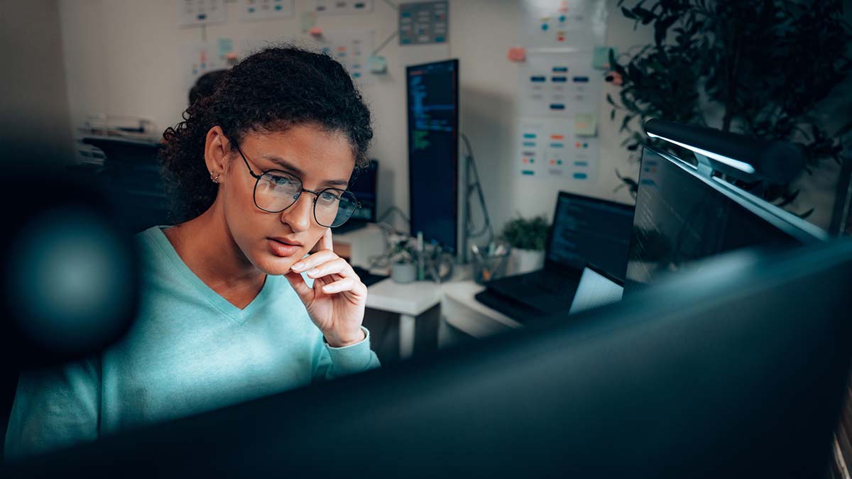 Assess and Learn | Young woman sitting at desk looking at computer