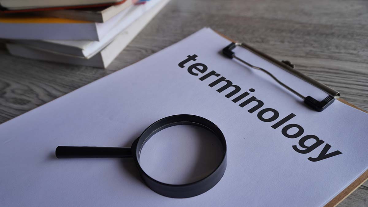Definition of Terms | Closeup image of books, magnifying glass and paper clipboard with text TERMINOLOGY.