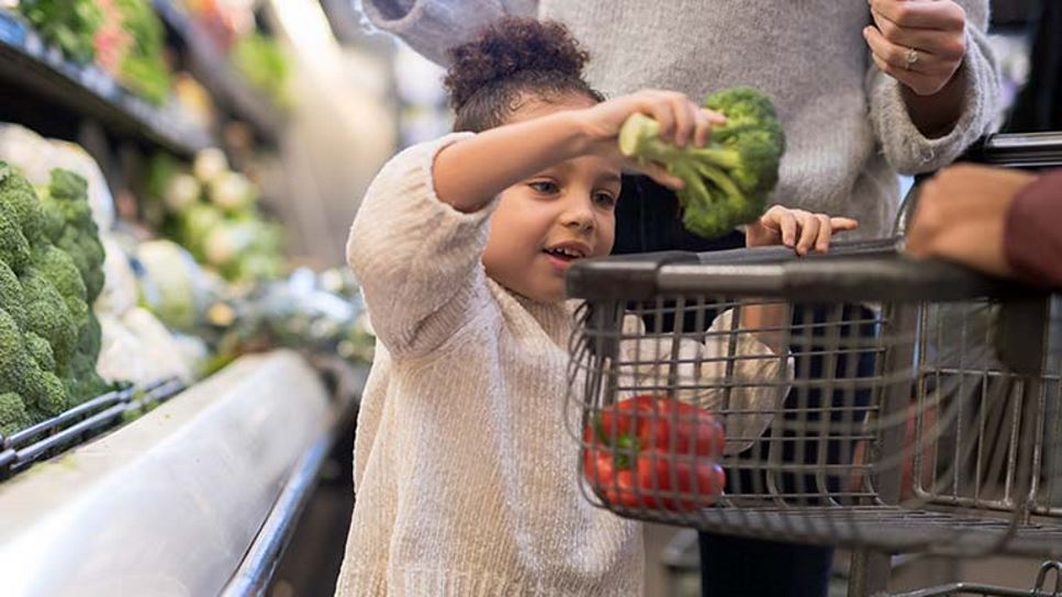 young girl choosing fresh vegetables at the supermarket