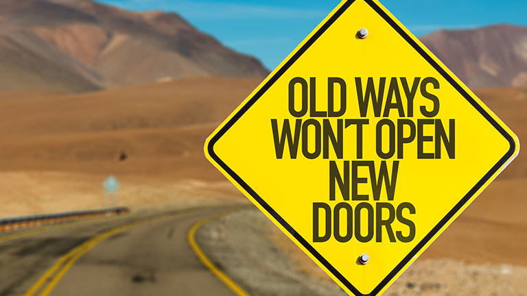 desert road sign reading "old ways won't open new doors"