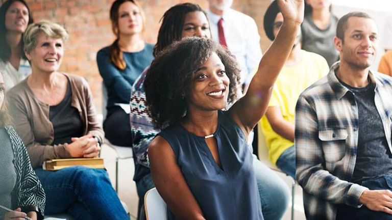 woman in crowd who raising her hand to volunteer