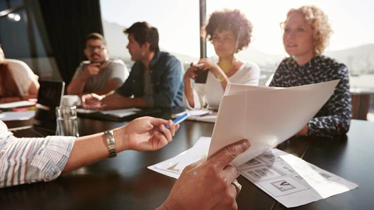 professionals in deep discussion sitting at a table reviewing documents