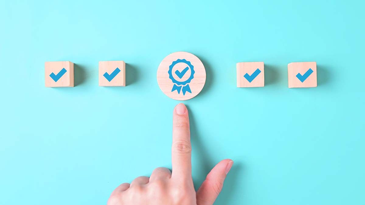 Checkmarks on wooden blocks with an index finger pointing to the circled checkmark in the middle