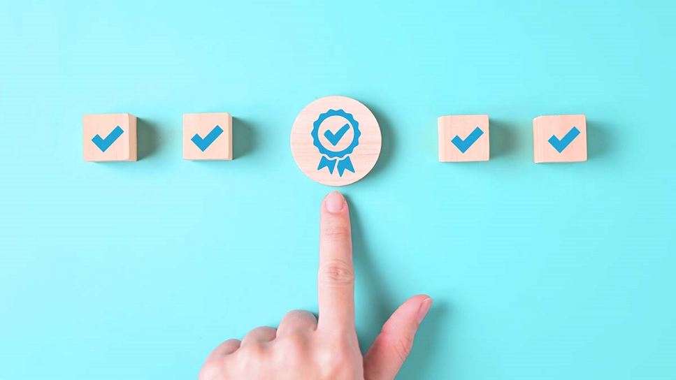 Checkmarks on wooden blocks with an index finger pointing to the circled checkmark in the middle