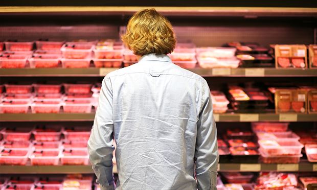 Man with alpha-gal syndrome, aka the red meat allergy from a tick bite, standing in a grocery store looking at fresh meats.