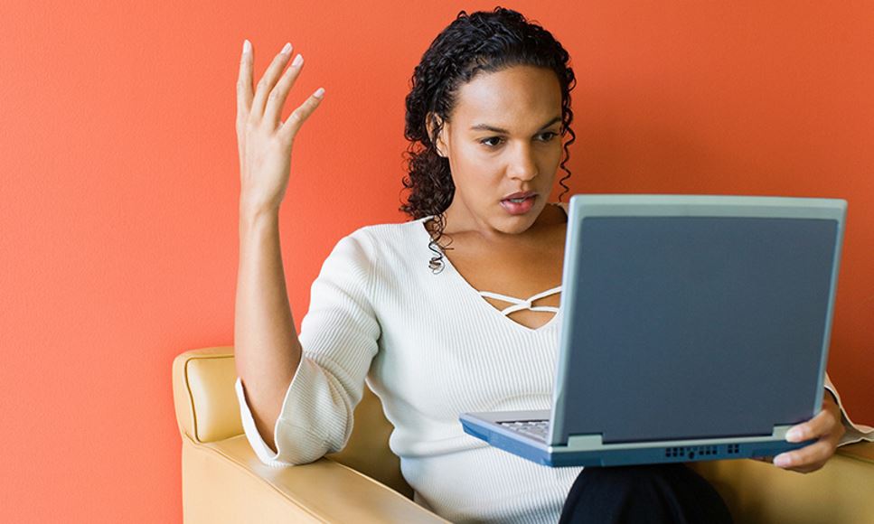 woman shocked and annoyed looking at her computer