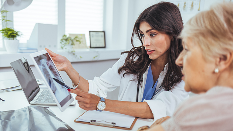 Female dietitian reviews x-rays and notes on nutrition for woman with lung cancer diagnosis.