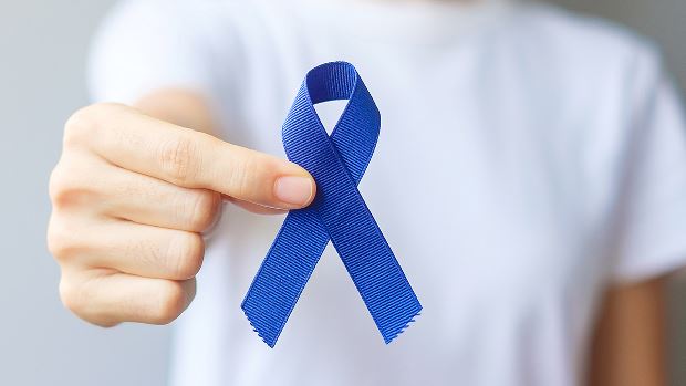 Person holding a blue ribbon, which signifies Colorectal Cancer Awareness Month, observed in March.