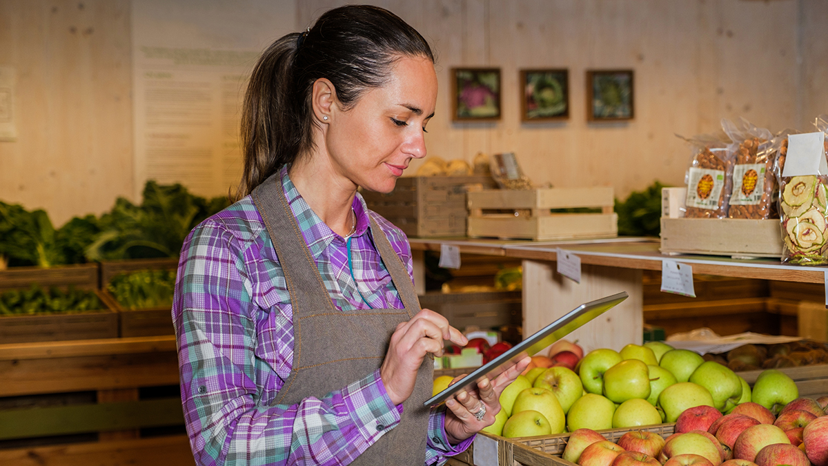 Woman working at a local grocery store or indoor farmers market taking inventory.