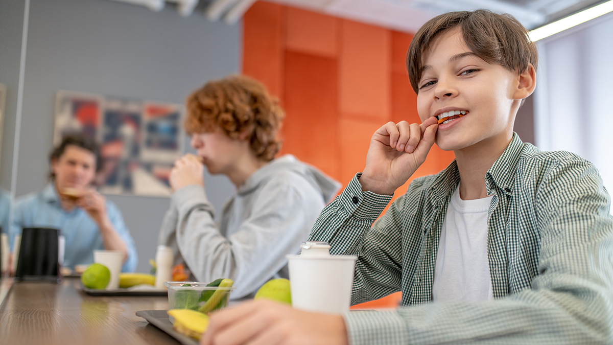 Students eat healthful foods at lunch during school, with plant-based options available as part of NSLP and SBP updates.