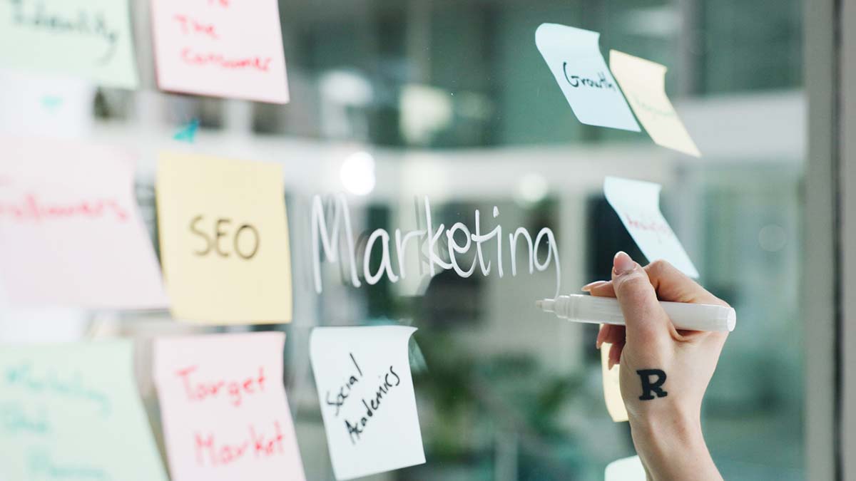 Membership Marketing Hub | Sticky notes and word "Marketing" written in white erasable marker on clear board